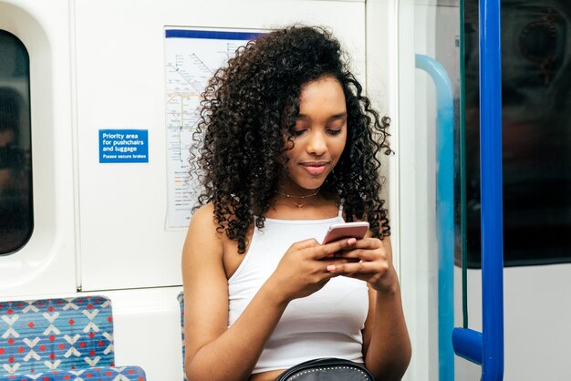 写真 携帯電話で地下に座っている若い黒人女性