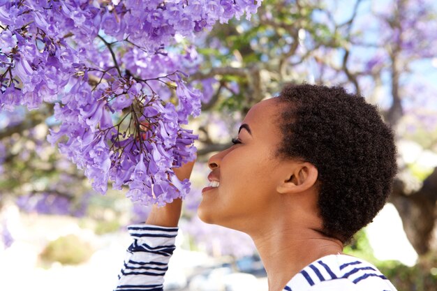 Молодая черная женщина, пахнущие цветами на дереве