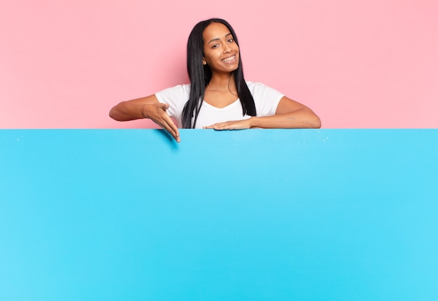 Young black woman smiling cheerfully, feeling happy and showing a concept