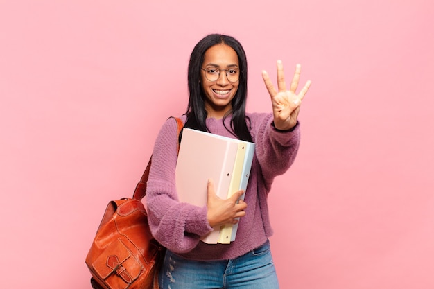 Photo young black woman smiling and looking friendly, showing number four or fourth with hand forward, counting down. student concept