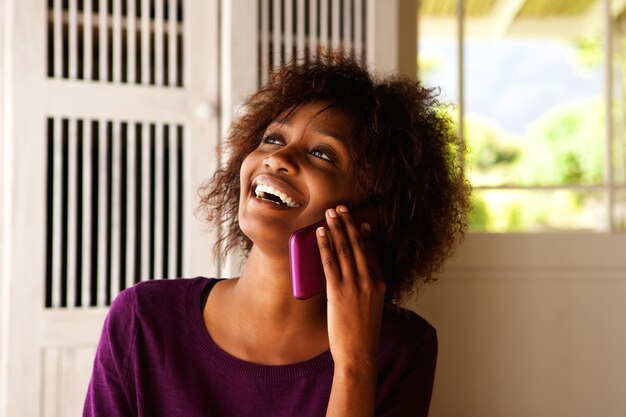 Молодая черная женщина улыбается с мобильного телефона