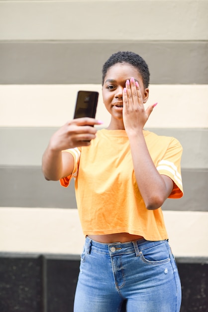 재미있는 식 야외와 selfie 사진을 찍는 젊은 흑인 여자.