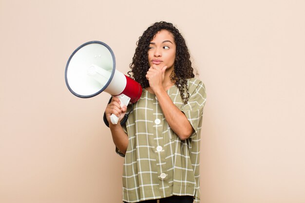 Young black woman thinking, holding a megaphone