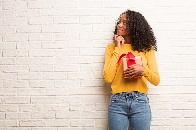 Young black woman thinking and looking up, confused about an idea, would be trying to find a solution