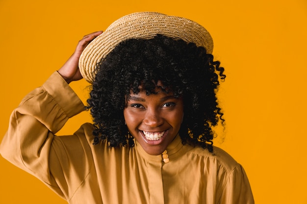 Young black woman toothy smiling and holding straw hat