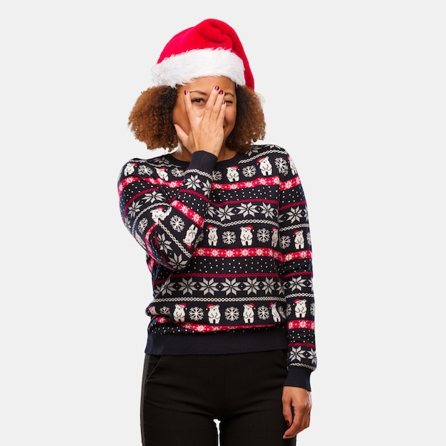 Young black woman in a trendy christmas sweater with print feels worried and scared