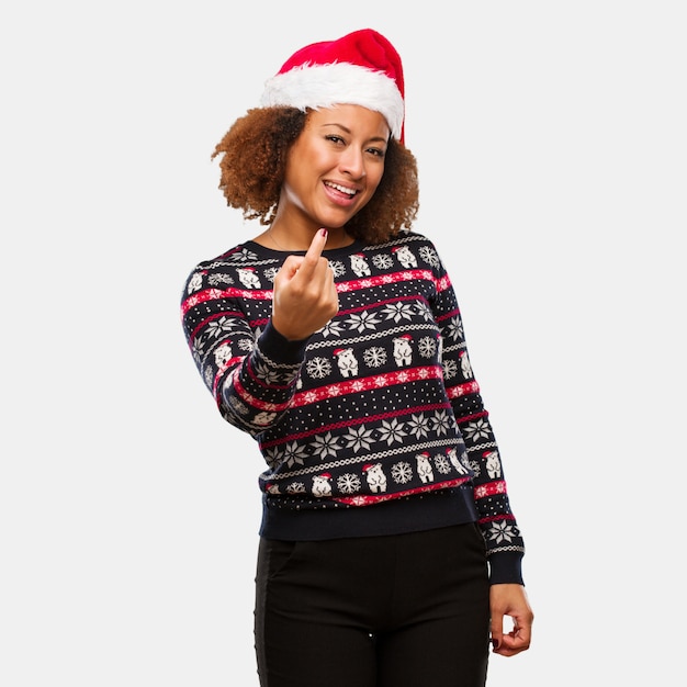 Young black woman in a trendy christmas sweater with print inviting to come