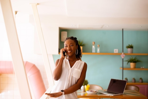 Giovane donna di colore che utilizza il telefono cellulare nella caffetteria