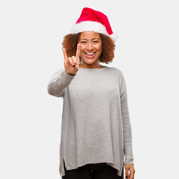 Young black woman wearing a santa hat doing a rock gesture