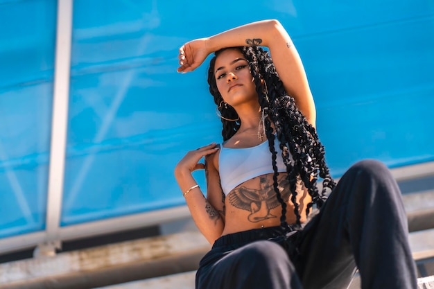 Young black woman with long braids and tattoos looking at camera copy space