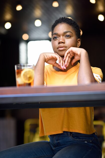 Young black woman with very short hair taking a glass of cold tea.