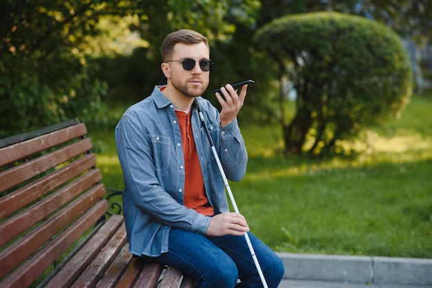 Young blinded man using phone and sending voice message