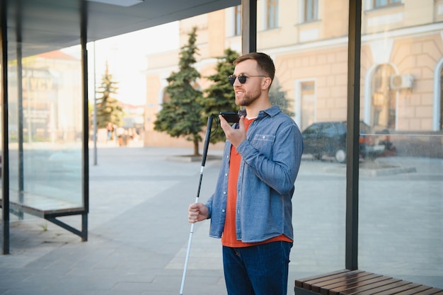 Young blinded man using phone and sending voice message