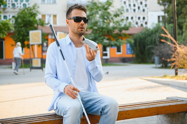 Young blinded man using phone and sending voice message