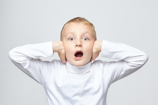 Young blond boy covers his ears