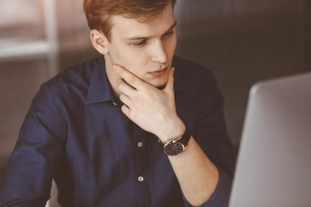 Photo young blond businessman feeling stress at workplace in a darkened office glare of light on the background startup business means working hard and out of time