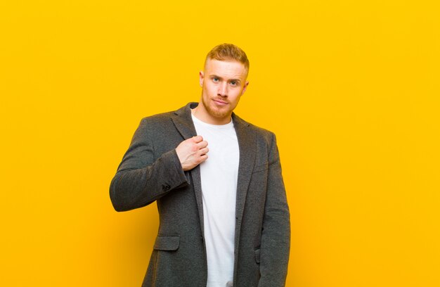 Young blond businessman framing or outlining own smile with both hands, looking positive and happy, wellness concept