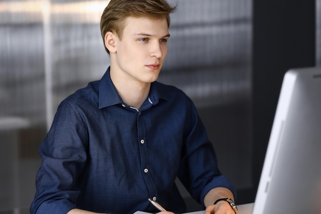 Photo young blond businessman working with computer. startup business means working hard and out of time for success achievement.