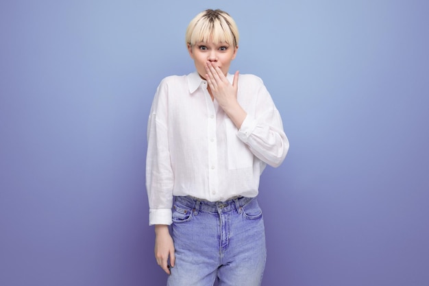 Young blond caucasian woman with a short haircut dressed in a white shirt keeps a secret