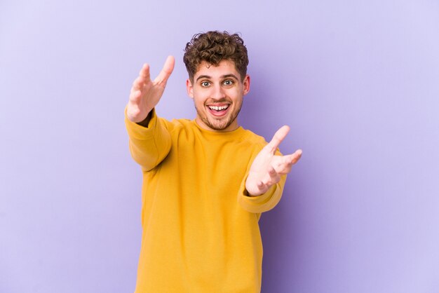 Young blond curly hair caucasian man feels confident giving a hug to the camera.