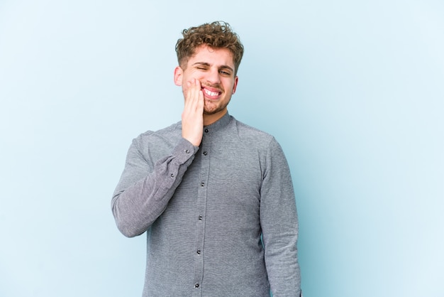 Young blond curly hair caucasian man having a strong teeth pain, molar ache.