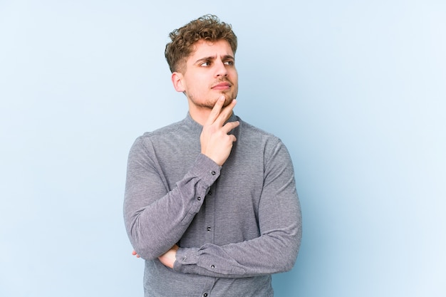 Young blond curly hair caucasian man isolated contemplating, planning a strategy, thinking about the way of a business.