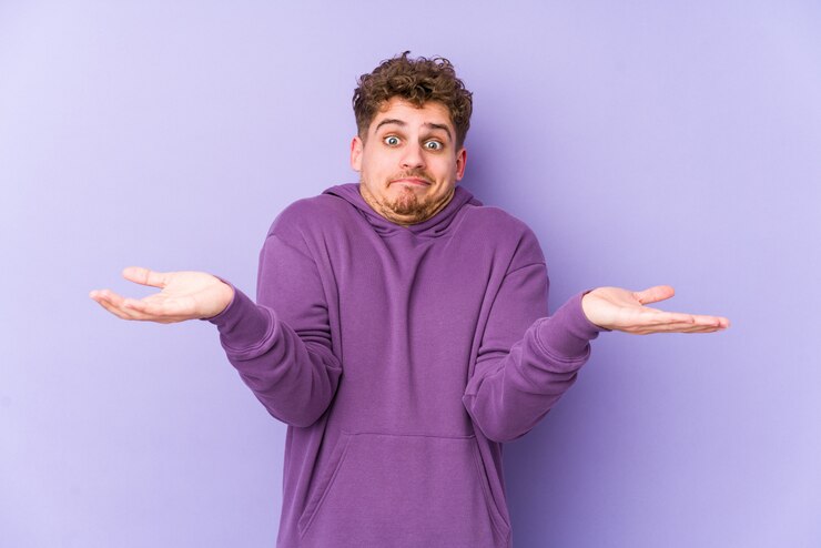 Photo young blond curly hair caucasian man isolated doubting and shrugging shoulders in questioning gesture.