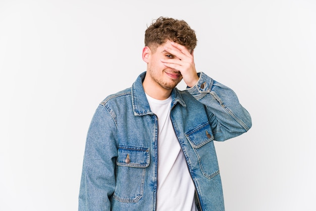 Young blond curly hair caucasian man isolated embarrassed coning face.