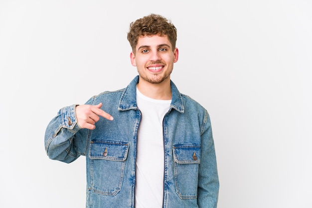 Young blond curly hair caucasian man isolated person pointing by hand to a shirt copy space, proud and confident