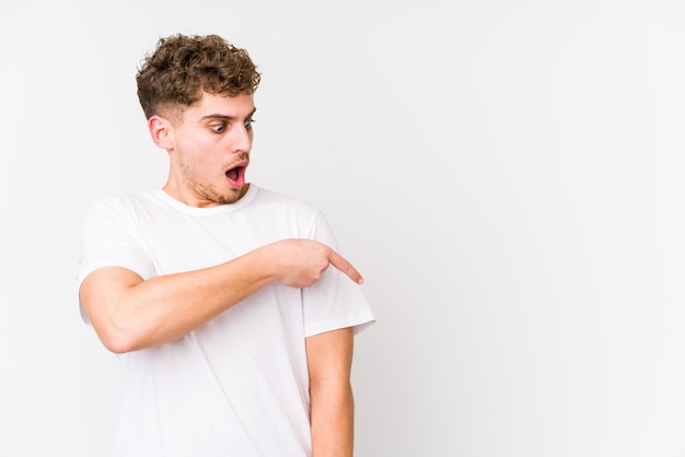 Young blond curly hair caucasian man isolated pointing to the side