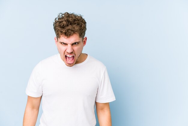 Young blond curly hair caucasian man isolated shouting very angry, rage concept, frustrated.