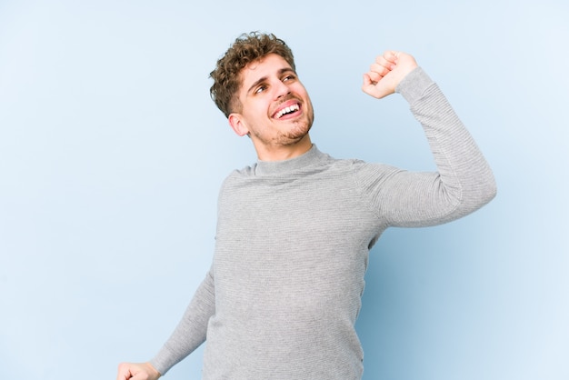 Young blond curly hair caucasian man isolated stretching arms, relaxed position.