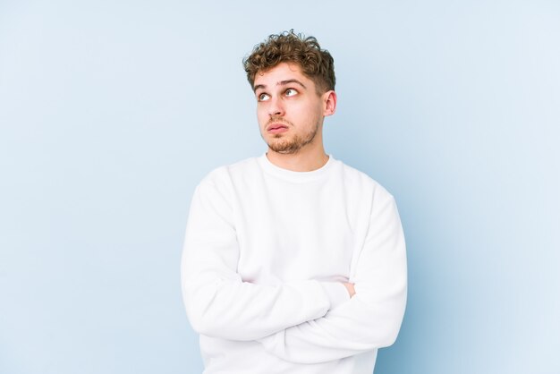 Young blond curly hair caucasian man isolated tired of a repetitive task.