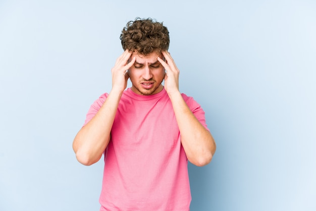 Young blond curly hair caucasian man isolated touching temples and having headache.