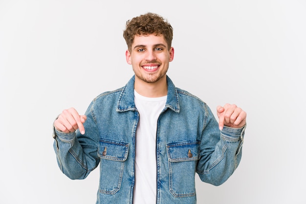 Young blond curly hair caucasian man points down with fingers