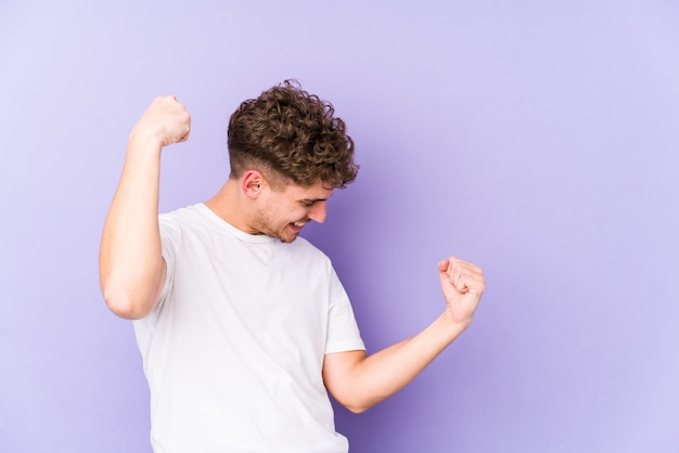 Young blond curly hair caucasian man raising fist after a victory