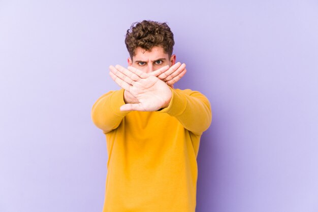 Young blond curly hair man doing a denial gesture