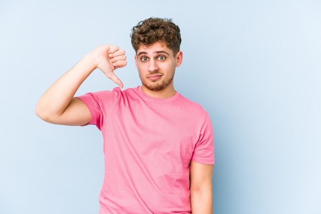 Young blond curly hair man showing a dislike gesture, thumbs down