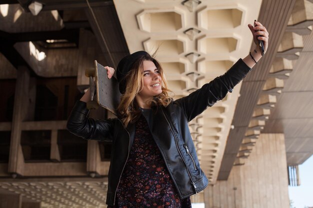 Young blond girl making selfie with the skateboard