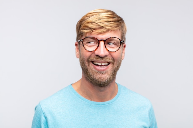 Young blond man happy and smiling