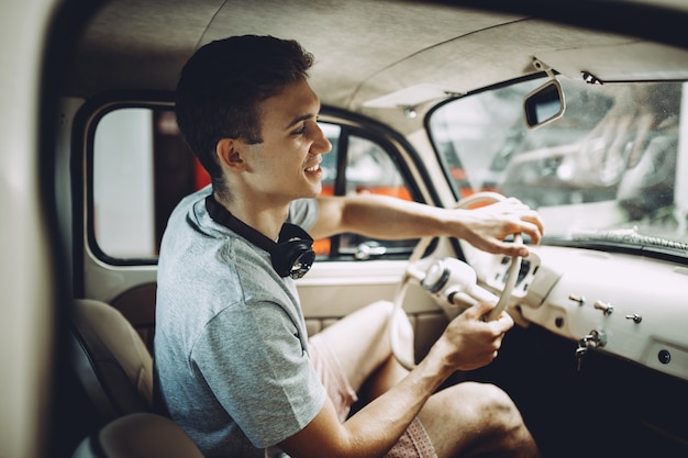 A young blond man is parking his ventage car.