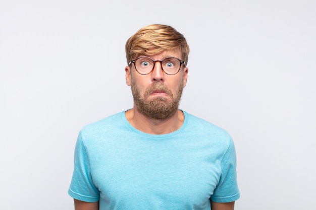 Young blond man scared expression