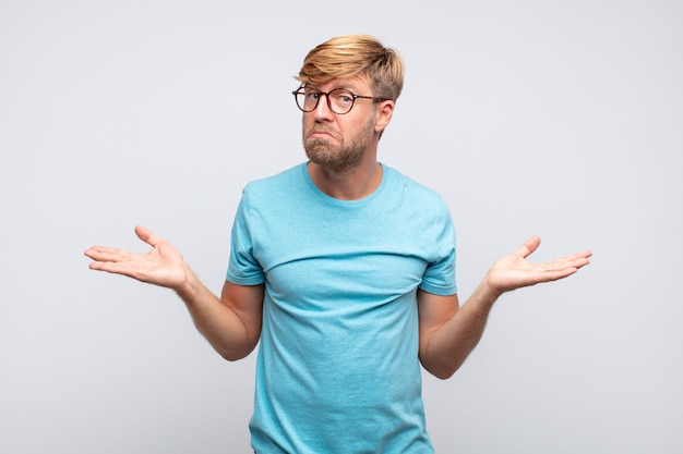 Young blond man thinking or doubting expression