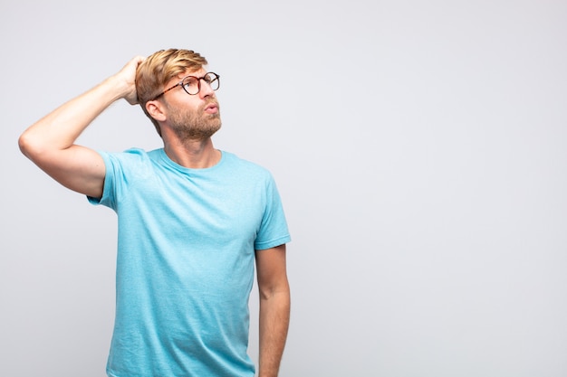 Young blond man thinking or doubting expression