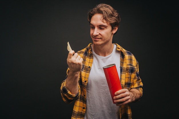 Young blond man in yellow shirt is holding chips