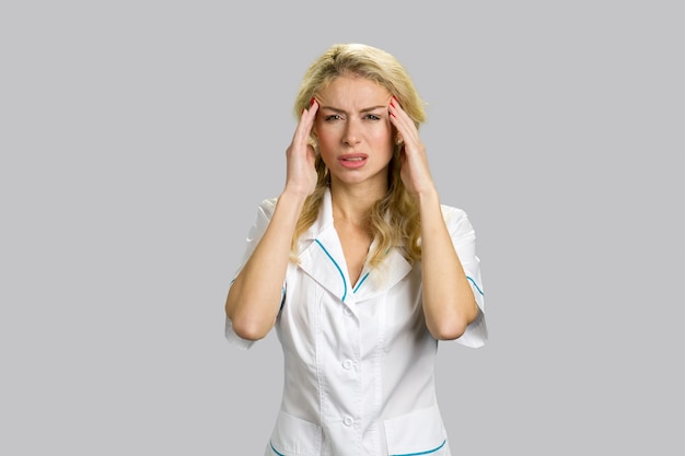 Young blond nurse having headache