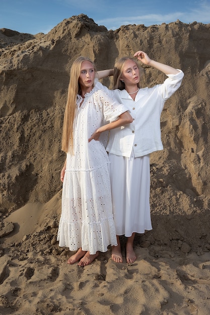 Young blond pretty twins posing at a sand quarry