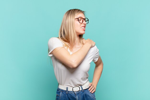피곤하고, 스트레스를 받고, 불안하고, 좌절하고, 우울하고, 등이나 목 통증으로 고통받는 젊은 금발의 예쁜 여성