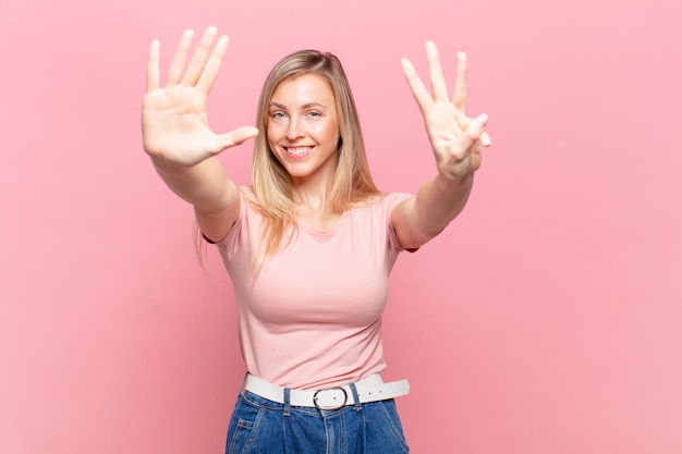 Young blond pretty woman smiling and looking friendly, showing number eight or eighth with hand forward, counting down