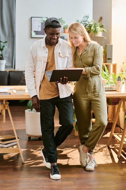 Young blond smiling businesswoman in casualwear helping her colleague